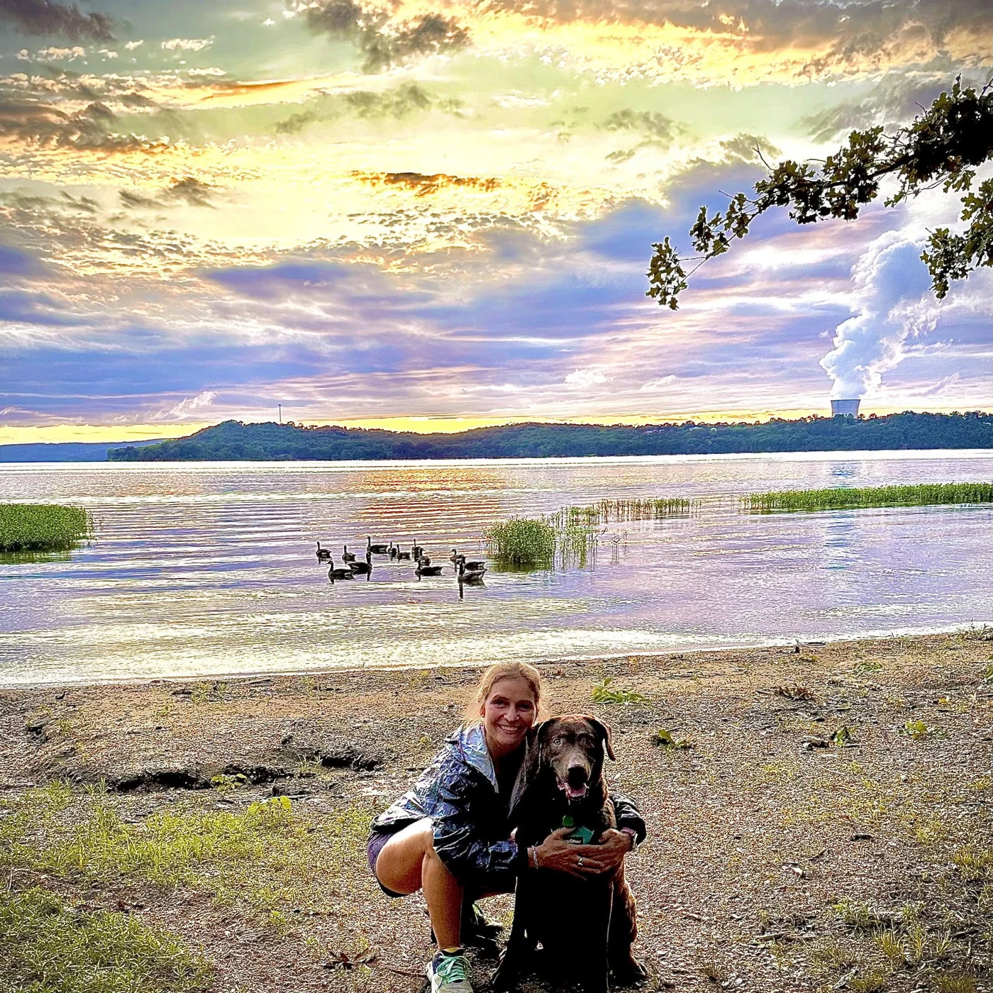 Tye Smith with a dog beside a lake at sunset